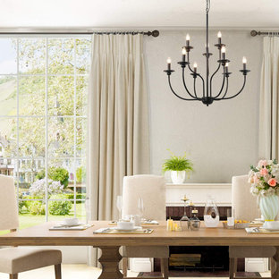 Immagine di una piccola sala da pranzo aperta verso la cucina minimalista con pareti bianche, pavimento in compensato, camino ad angolo, cornice del camino in legno e pavimento marrone