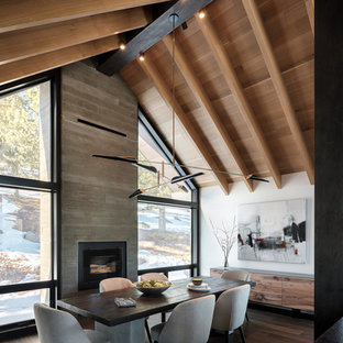 Idée de décoration pour une salle à manger ouverte sur la cuisine chalet de taille moyenne avec un mur blanc, un sol en bois brun, une cheminée standard et un manteau de cheminée en béton.