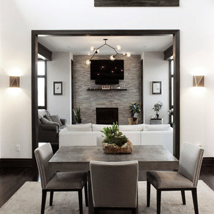 Ejemplo de comedor contemporáneo, de tamaño medio, abierto, con paredes blancas, suelo de madera oscura, chimenea tradicional, marco de chimenea de piedra y suelo marrón