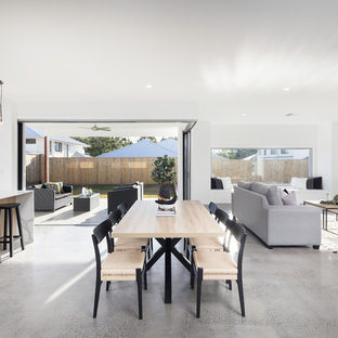 This is an example of a scandinavian open plan dining in Brisbane with white walls, concrete floors and brown floor.