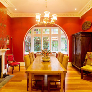 Immagine di una sala da pranzo classica con pareti rosse e camino classico
