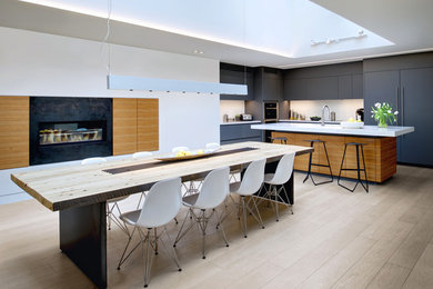 Стильный дизайн: кухня-столовая в скандинавском стиле с белыми стенами, светлым паркетным полом, горизонтальным камином и фасадом камина из металла - последний тренд