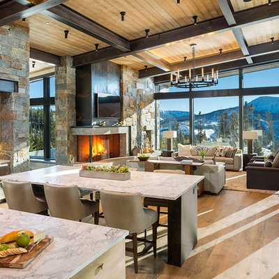 Example of a large mountain style medium tone wood floor and brown floor great room design in Other with a stone fireplace and a corner fireplace