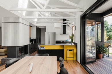 Idée de décoration pour une grande salle à manger ouverte sur la cuisine vintage avec un mur blanc, un sol en bois brun, une cheminée double-face, un manteau de cheminée en carrelage et éclairage.