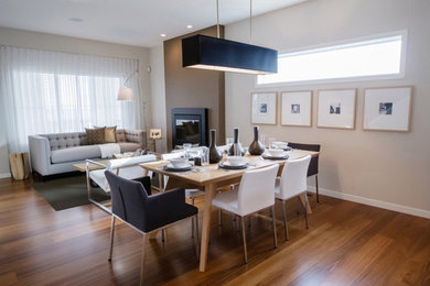 Medium sized contemporary open plan dining room in New York with beige walls, medium hardwood flooring, a hanging fireplace, a plastered fireplace surround and brown floors.