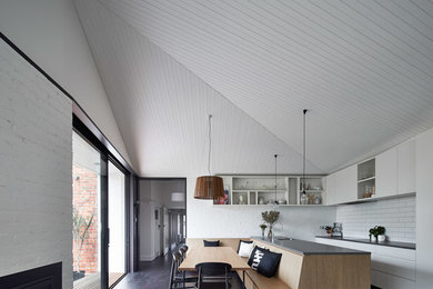 Diseño de comedor de cocina minimalista con paredes blancas, suelo de madera oscura, todas las chimeneas y marco de chimenea de ladrillo