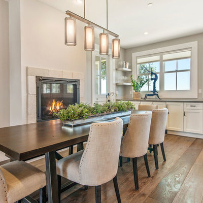 Example of a mid-sized cottage dark wood floor kitchen/dining room combo design in San Francisco with gray walls, a standard fireplace and a stone fireplace