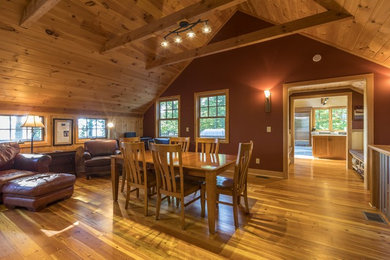 Great room - mid-sized rustic medium tone wood floor and brown floor great room idea in Other with red walls and no fireplace