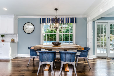 Cette image montre une salle à manger ouverte sur la cuisine traditionnelle de taille moyenne avec un mur bleu, parquet foncé, aucune cheminée et un sol marron.