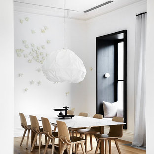 Inspiration for a scandinavian separate dining room in Melbourne with white walls, medium hardwood floors and brown floor.
