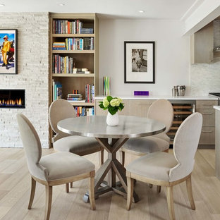 Esempio di una piccola sala da pranzo aperta verso la cucina minimalista con pareti grigie, parquet chiaro, pavimento beige, camino lineare Ribbon e cornice del camino in pietra