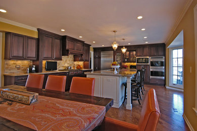 На фото: большая кухня-столовая в стиле неоклассика (современная классика) с желтыми стенами, темным паркетным полом и коричневым полом без камина с