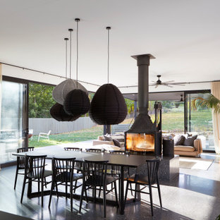 Esempio di una grande sala da pranzo minimal con pareti bianche, pavimento in cemento, pavimento nero e stufa a legna