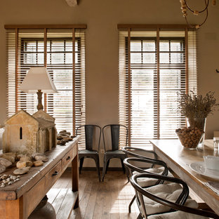 Immagine di una grande sala da pranzo aperta verso il soggiorno country con pareti beige, pavimento in legno massello medio e nessun camino