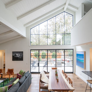 Cette photo montre une salle à manger ouverte sur le salon moderne de taille moyenne avec un mur blanc, un sol en bois brun, un sol marron et un plafond en lambris de bois.