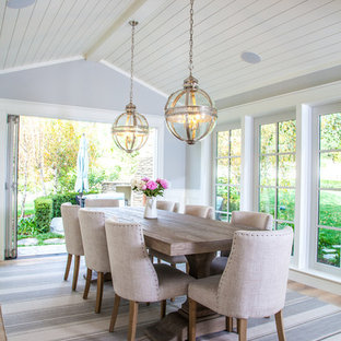 Immagine di una sala da pranzo country chiusa e di medie dimensioni con pareti grigie e parquet chiaro