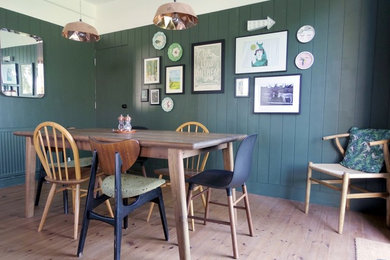 Imagen de comedor ecléctico abierto con paredes verdes y suelo de madera clara