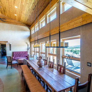 Modelo de comedor de cocina de estilo americano, de tamaño medio, con paredes beige, suelo de cemento, estufa de leña, marco de chimenea de hormigón y suelo verde