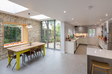 Immagine di un'ampia sala da pranzo aperta verso la cucina minimal con pareti grigie e pavimento in cemento