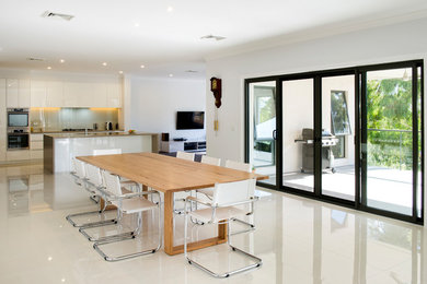 На фото: столовая в стиле модернизм с белыми стенами, полом из керамической плитки и белым полом с