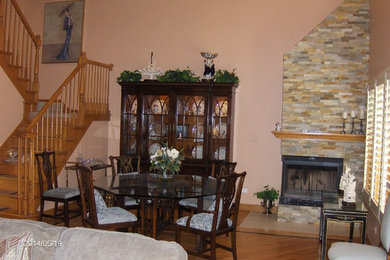 Ejemplo de comedor de cocina bohemio de tamaño medio con parades naranjas, suelo de madera oscura, chimenea de esquina y marco de chimenea de piedra