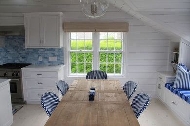 Imagen de comedor de cocina costero de tamaño medio sin chimenea con paredes blancas, suelo de madera clara y suelo beige