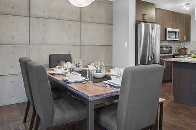 Cette photo montre une salle à manger ouverte sur le salon tendance de taille moyenne avec parquet foncé, un sol marron et un mur gris.
