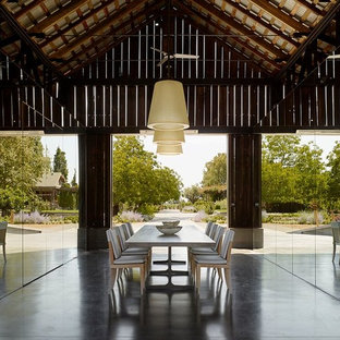 Foto di una grande sala da pranzo country chiusa con pareti con effetto metallico, pavimento in cemento e nessun camino