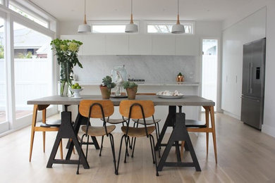 Mid-sized elegant light wood floor kitchen/dining room combo photo in Auckland with white walls and no fireplace