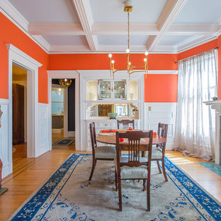 Idee per una sala da pranzo classica chiusa con pareti arancioni, pavimento in legno massello medio, camino classico e cornice del camino piastrellata