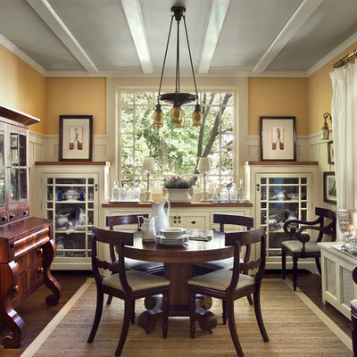 Example of a classic dark wood floor enclosed dining room design in New York with yellow walls