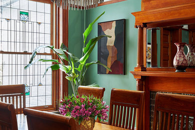 Immagine di una sala da pranzo tradizionale chiusa e di medie dimensioni con pareti verdi, camino classico e cornice del camino piastrellata