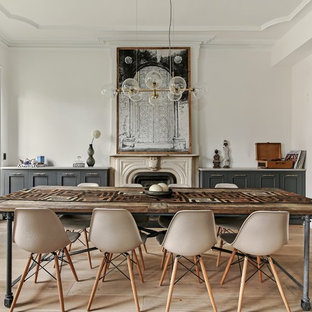 This is an example of a mid-sized eclectic separate dining room in New York with white walls, light hardwood floors, a standard fireplace, a stone fireplace surround and beige floor.