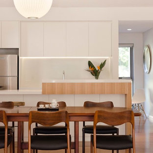 This is an example of a contemporary kitchen/dining combo in Sydney with white walls, medium hardwood floors and brown floor.