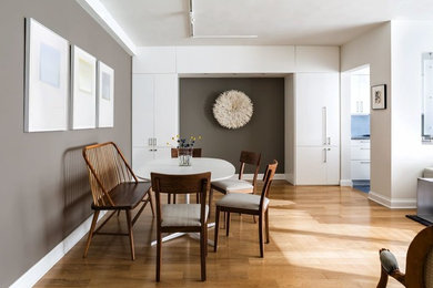 Cette image montre une salle à manger ouverte sur le salon design avec un mur gris, un sol en bois brun et aucune cheminée.