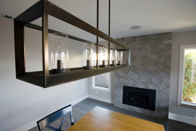 Imagen de comedor actual de tamaño medio abierto con todas las chimeneas, marco de chimenea de baldosas y/o azulejos y suelo gris