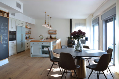 Cette photo montre une salle à manger ouverte sur la cuisine tendance de taille moyenne avec un mur blanc, parquet clair et une cheminée standard.