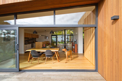 Kleine Maritime Wohnküche mit weißer Wandfarbe, hellem Holzboden, Kaminofen, Kaminumrandung aus Stein und beigem Boden in Auckland
