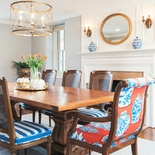 Esempio di una sala da pranzo chic chiusa con pareti grigie, parquet scuro, camino classico e cornice del camino in pietra