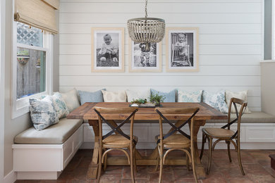 Cette image montre une salle à manger marine avec un mur blanc, tomettes au sol et un sol marron.