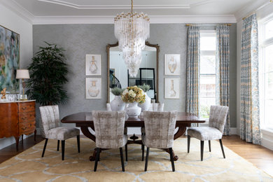 Large transitional medium tone wood floor, brown floor and wallpaper enclosed dining room photo in Dallas with gray walls