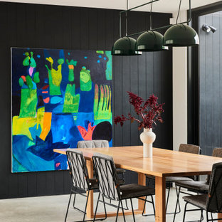 Photo of a mid-sized contemporary kitchen/dining combo with black walls, concrete floors, grey floor and planked wall panelling.