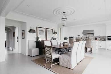 Esempio di una sala da pranzo aperta verso la cucina chic di medie dimensioni con pareti bianche, pavimento in cemento e pavimento grigio