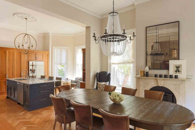 Example of a classic medium tone wood floor and orange floor kitchen/dining room combo design in Boston with beige walls and a standard fireplace