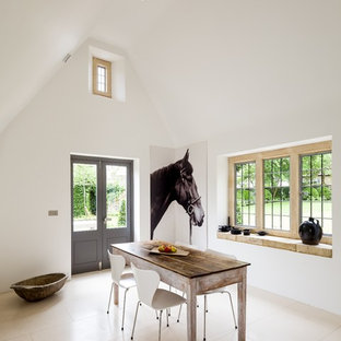 This is an example of a farmhouse enclosed dining room in Gloucestershire with white walls, limestone flooring and beige floors.