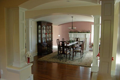 Exemple d'une salle à manger chic fermée et de taille moyenne avec un mur rose et un sol en bois brun.