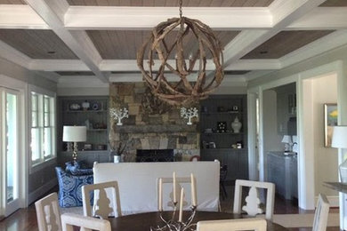 This is an example of a large rustic kitchen/dining room in Other with beige walls, dark hardwood flooring, a standard fireplace, a stone fireplace surround and brown floors.