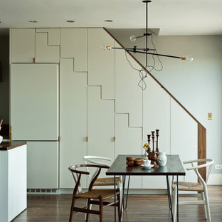 Foto di una sala da pranzo aperta verso la cucina minimalista con pareti grigie e parquet scuro