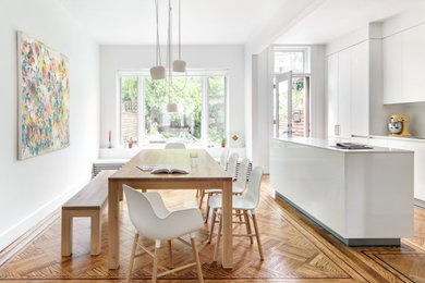 Trendy medium tone wood floor and brown floor dining room photo in New York with white walls