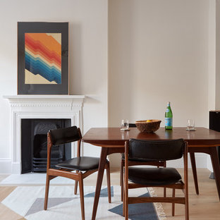 Inspiration for a medium sized scandi dining room in London with white walls, light hardwood flooring, a wood burning stove and a plastered fireplace surround.
